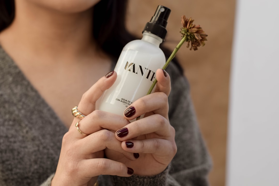 A woman misting her face with setting spray to lock in her summer makeup against humidity