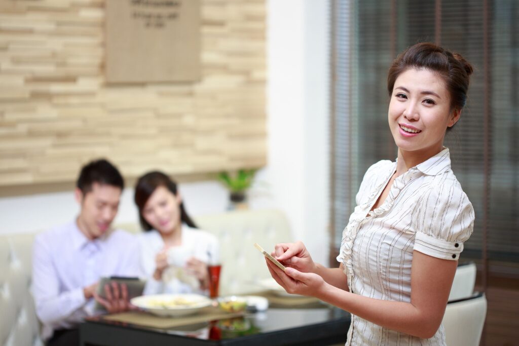 Professional waiter serving customers at a restaurant table, representing waiter respect in hospitality