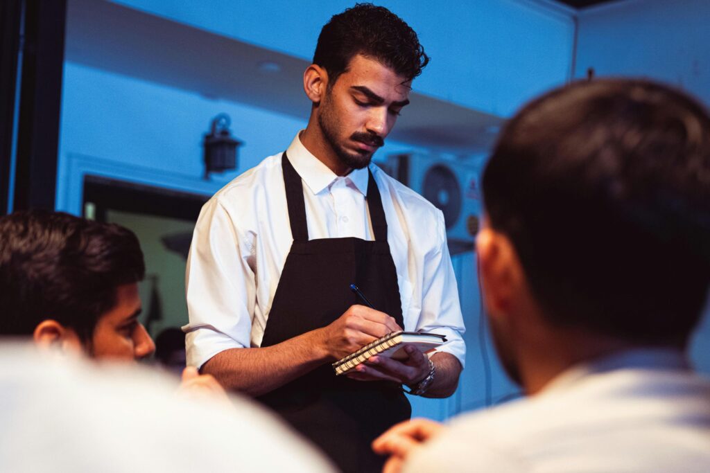 Professional waiter taking the menu choix to customers at a restaurant table, representing waiter respect in hospitality