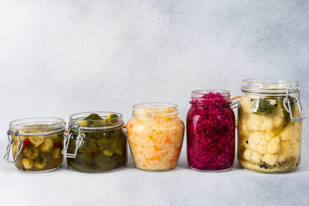 Traditional fermented vegetables in a ceramic crock with fresh cabbage and herbs