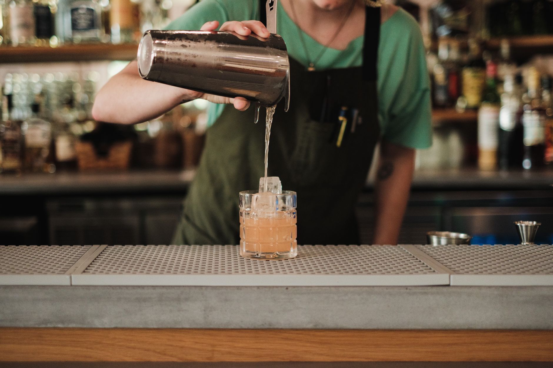A restaurant bartender applying mixology training skills to build a seasonal cocktail with fresh local ingredients