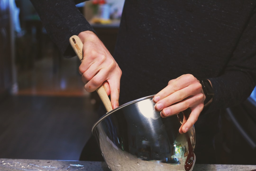 Una persona mescola caramello miso in una ciotola di dolce, dimostrando come il miso crea combinazioni di sapore dolce audace in cucina.
