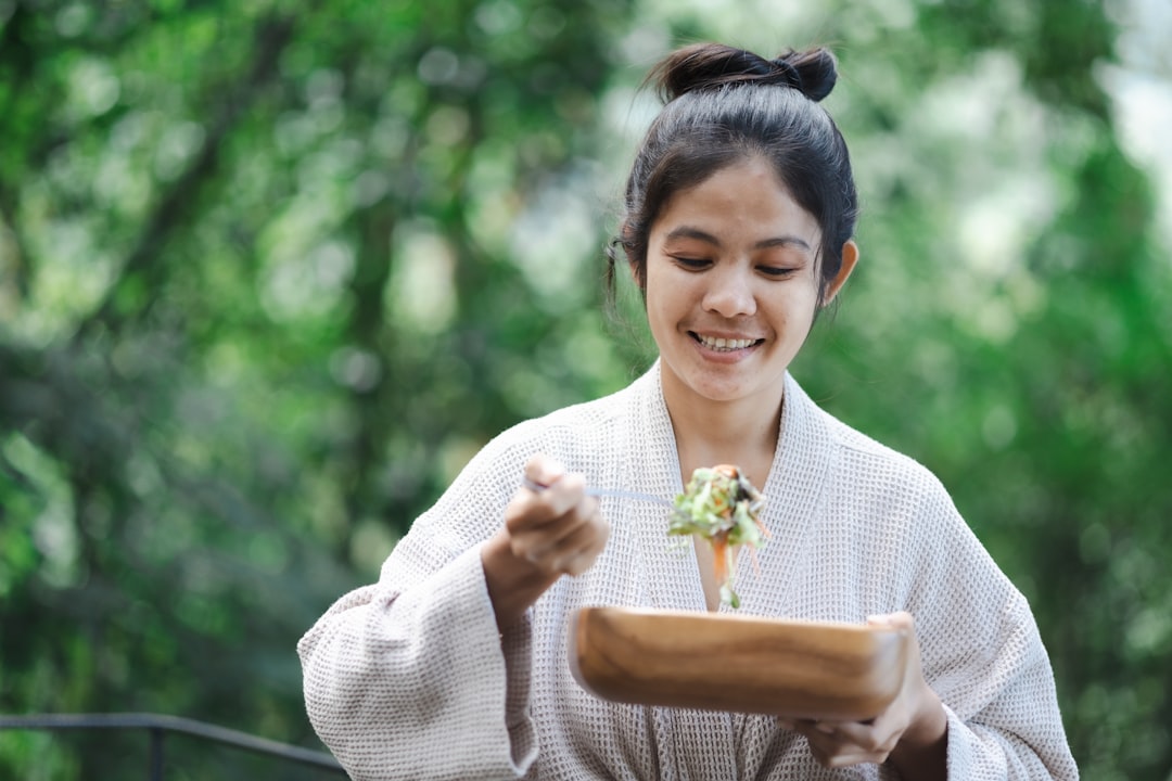Una donna assaggia verdure glassate al miso arrostito al bancone della cucina, esplorando i molteplici usi culinari dell'impasto di miso.