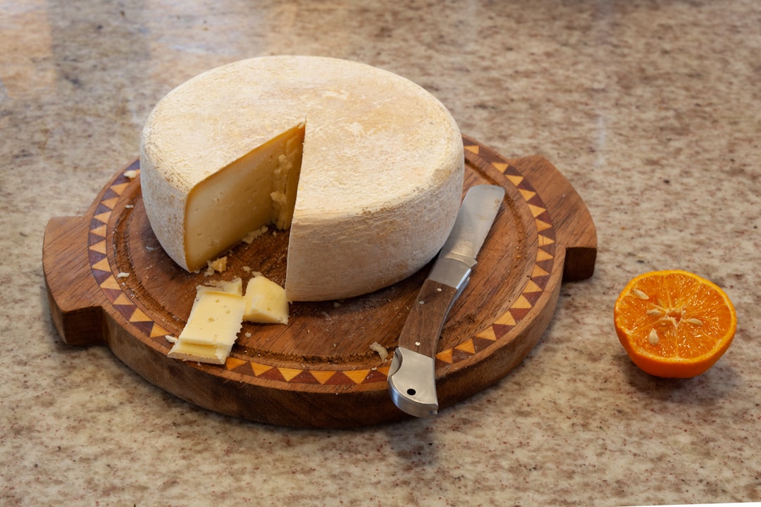 Um queijeiro fatia uma fatia de queijo artesanal em um balcão especializado, exibindo a precisão da seleção de queijos artesanais