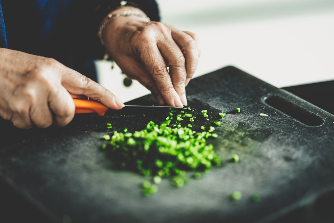 Uno chef che taglia finemente le erbe aromatiche e dispone spezie calde su un tagliere di legno per preparare un autentico chermoula marocchino.