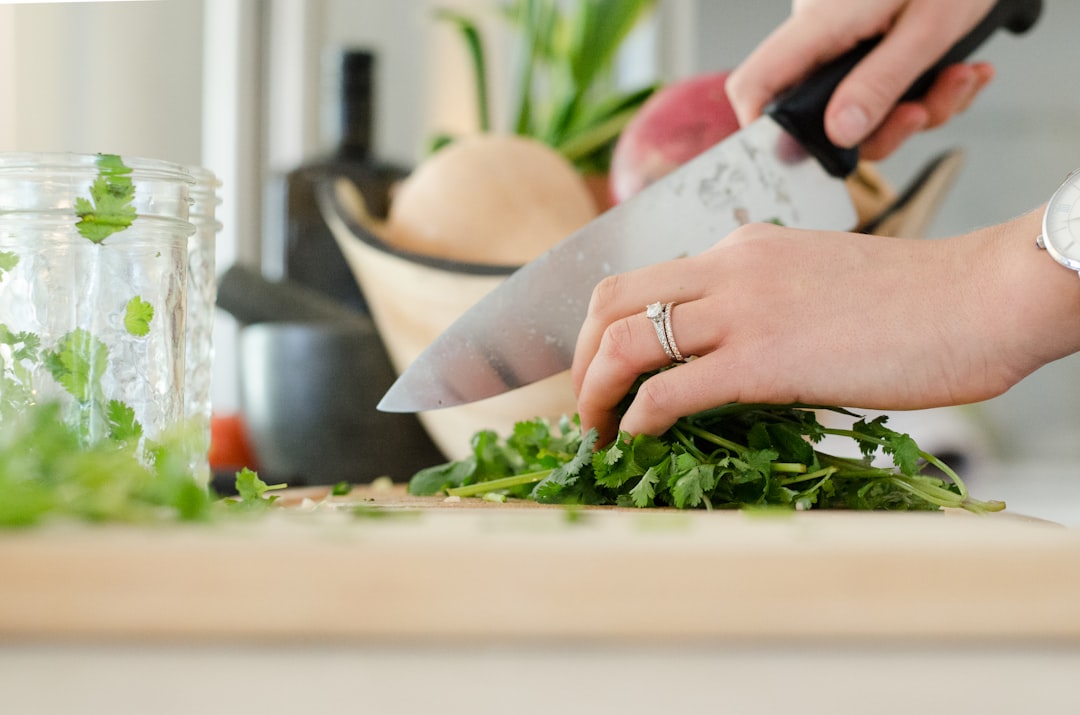 Un cuoco casalingo che utilizza la tecnica della mano a artiglio per esercitare le tecniche di coltello mentre taglia i prodotti estivi