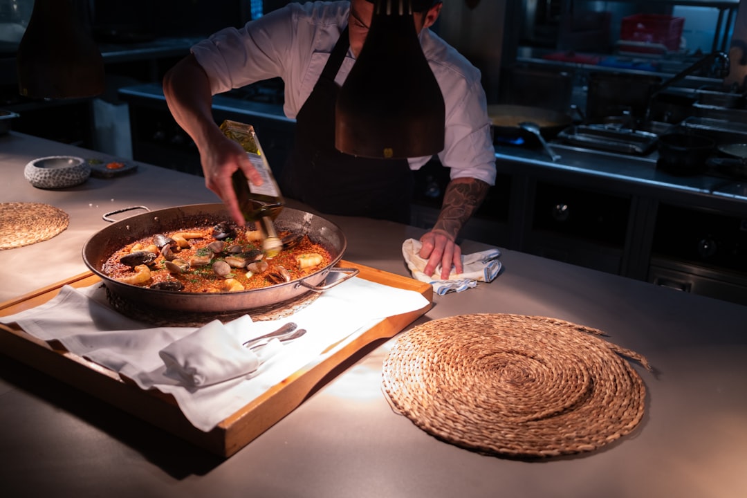 Una persona che serve un tajine di pesce marocchino in un ricco chermoula marocchino con limone conservato e erbe fresche.