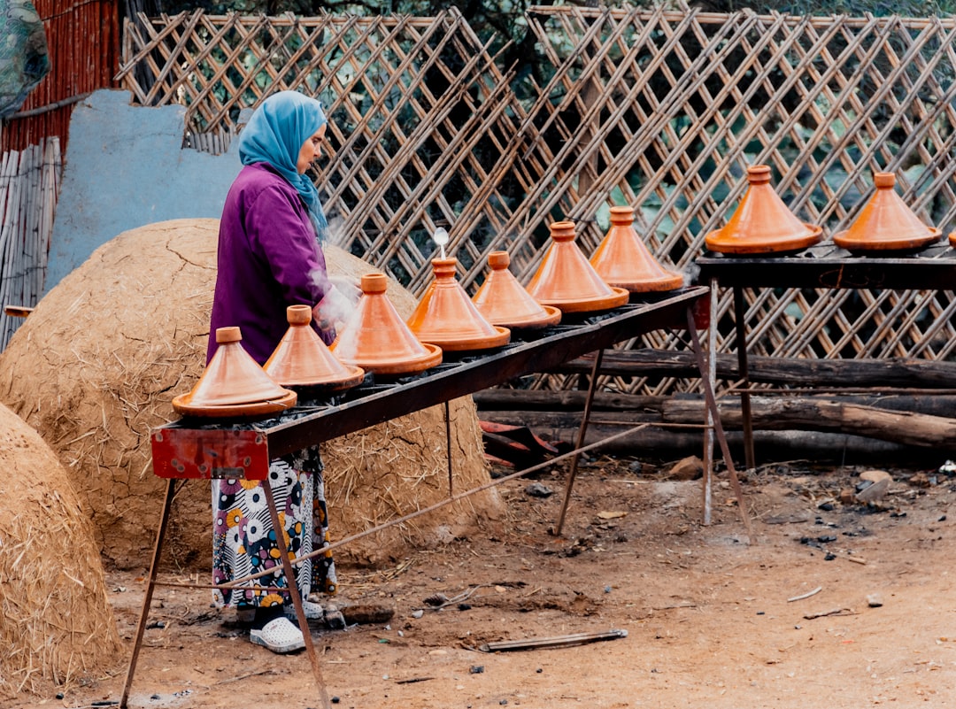 Um cozinheiro doméstico preparando cozidos lentos em um recipiente tradicional de tajine de barro com especiarias quentes e cordeiro