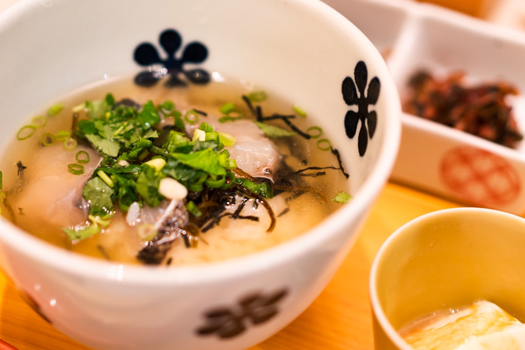 A home cook stirs fermented miso paste into a plant-based broth creating deep flavour without meat or stock.