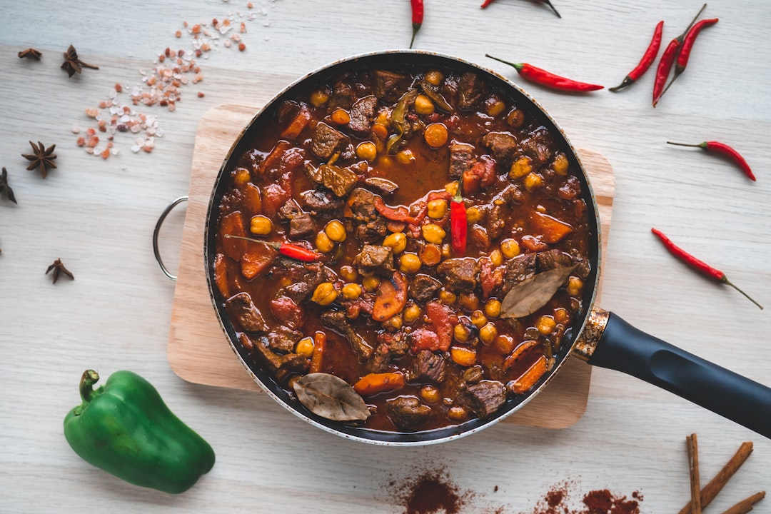 A chef blooming spices in oil before adding slow cooked beans to a deep pot in a professional kitchen