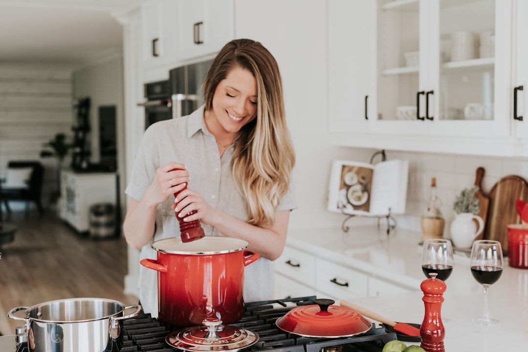 A home cook carefully adjusting seasoning over a colorful bowl of international food, demonstrating how to taste seasoning.