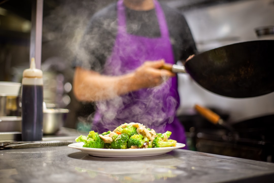 A man adding global condiments to a colorful stir-fry in a home kitchen wok