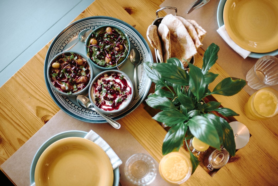 A person ladling slow cooked beans into a bowl at a beautifully set dining table, ready to eat