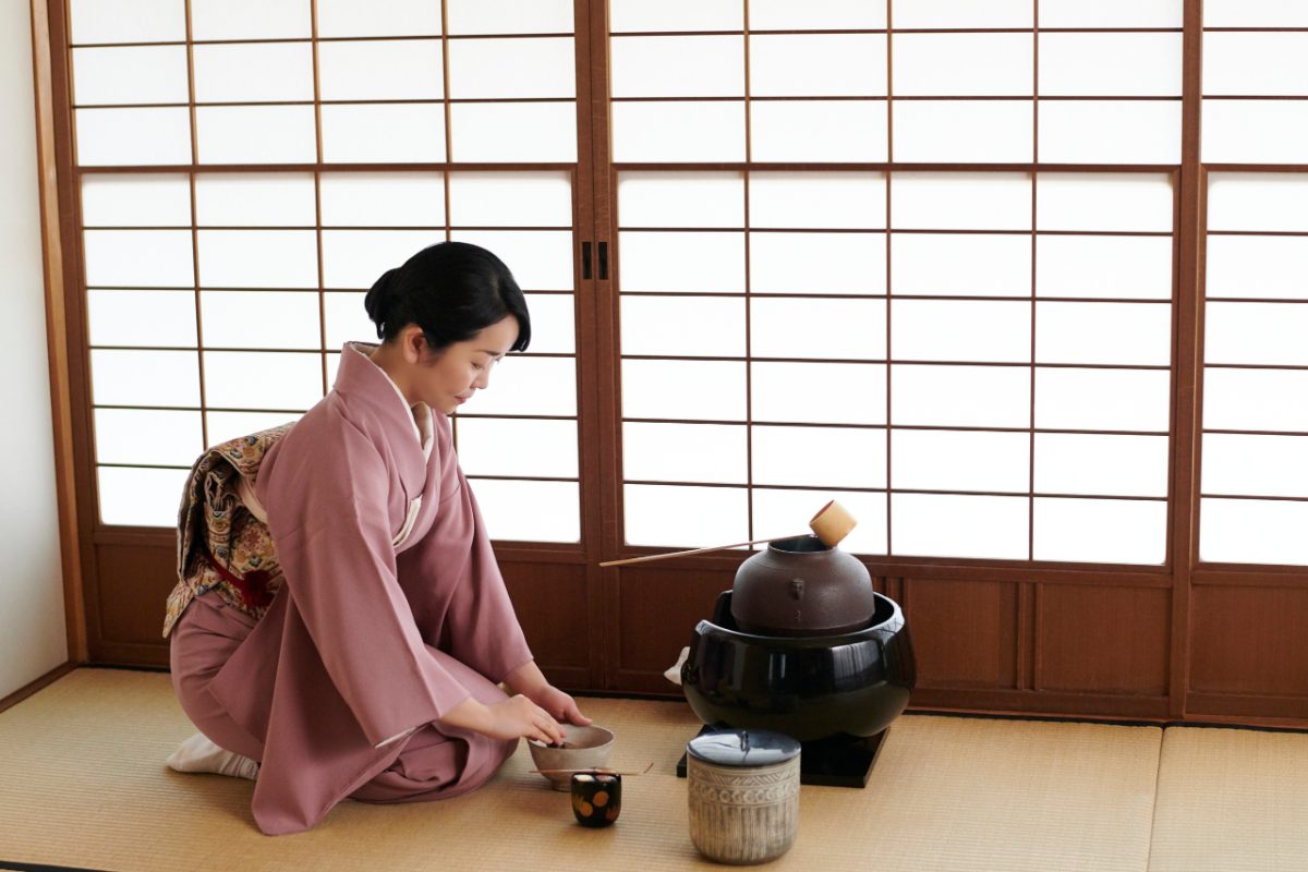 Una donna si gode una cerimonia del tè tradizionale al chiuso a Tokyo durante la stagione delle piogge, abbracciando la calma bellezza dello tsuyu.