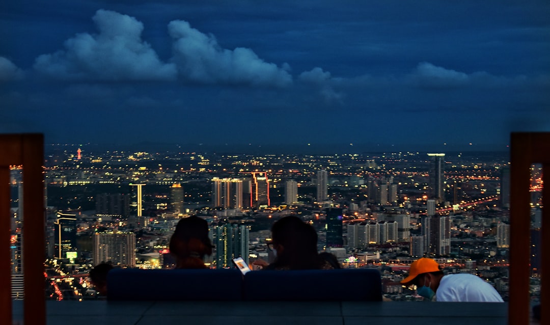 Un couple assis dans un bar sur le toit au-dessus de Tokyo, profitant de cocktails au coucher du soleil avec un salon panoramique à l'horizon en arrière-plan.