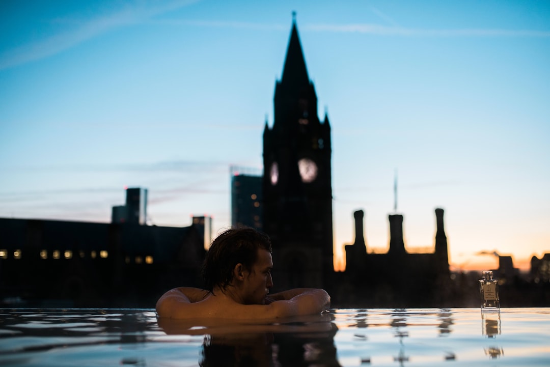 Un uomo si immerge in una vasca all'aperto su una terrazza a Tokyo, con le luci della città riflesse sull'acqua minerale scura sotto il cielo notturno.