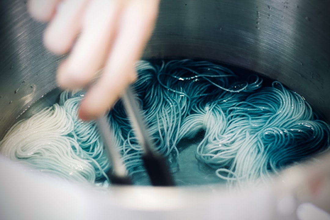 Una persona estrae un tessuto tinto con indaco da una tinozza in un laboratorio di Tokyo, osservando il colore blu che si sviluppa.