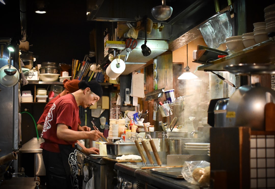 Uno chef di soba affetta con cura la pasta di grano saraceno stesa a mano in una cucina di Tokyo, preparando soba fredda per il servizio del pranzo.