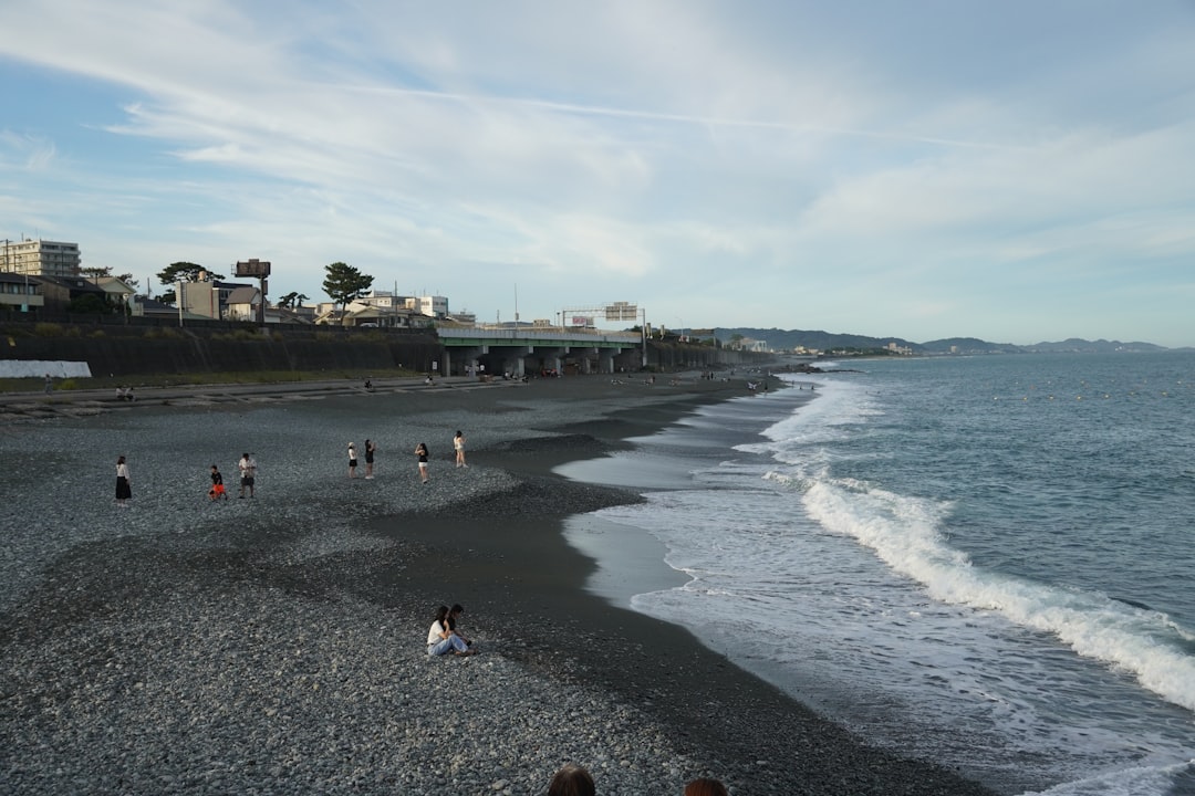 Una famiglia siede sulla sabbia presso una spiaggia urbana di Tokyo al Kasai Rinkai Park, godendosi la brezza marina in un umido pomeriggio estivo