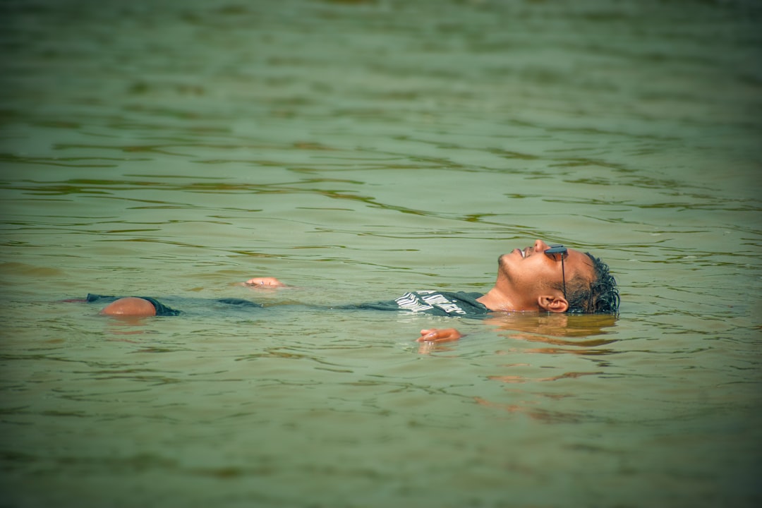 Un ospite galleggia pacificamente in acqua salata calda durante una sessione di terapia di galleggiamento, occhi chiusi in silenzio.