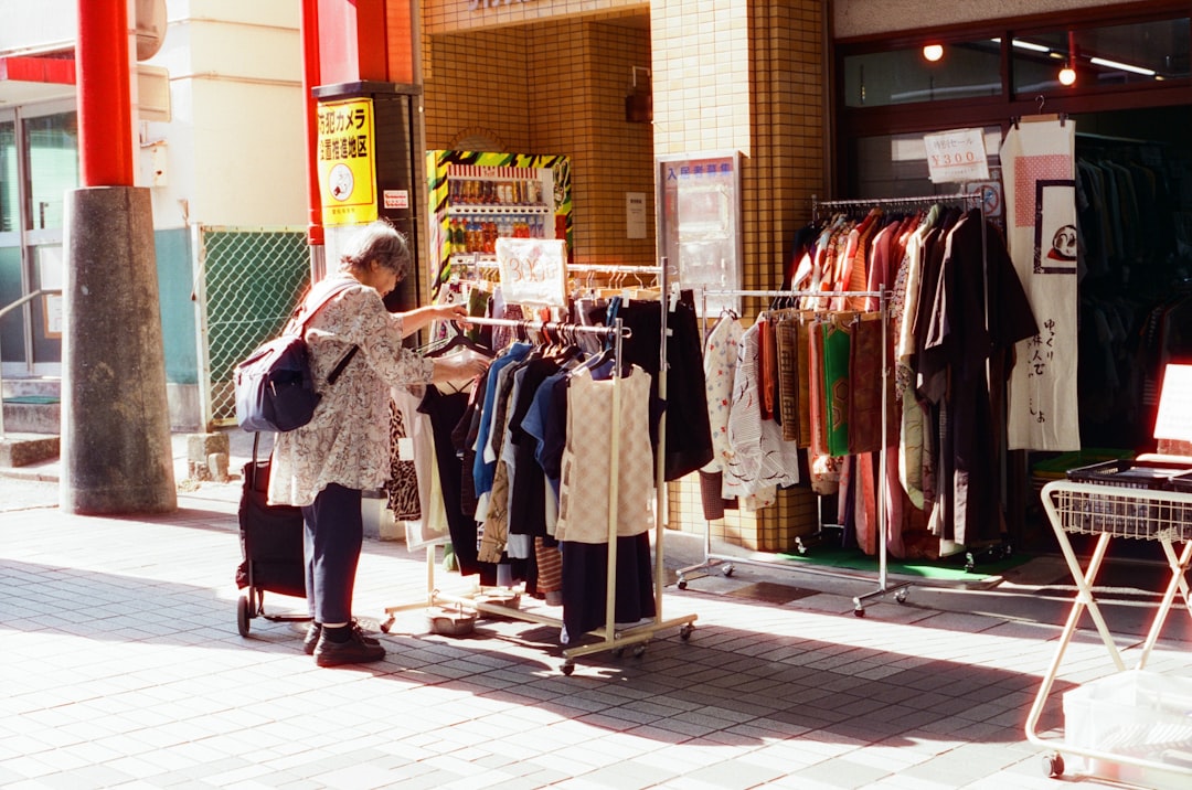 Un acheteur tient une veste de seconde main dans une rue calme de Tokyo, reflétant le rituel minutieux du shopping de seconde main à Tokyo