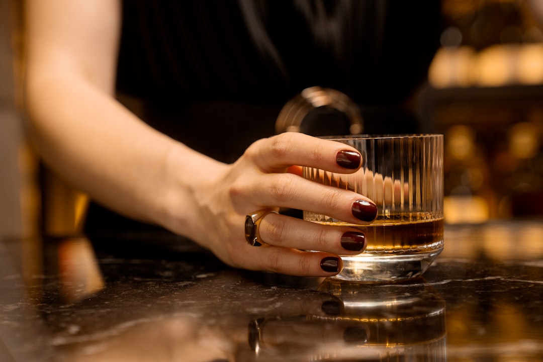 Un client savoure un vol de whisky japonais rare dans un bar d'hôtel intime à Tokyo, le verre levé vers la lumière