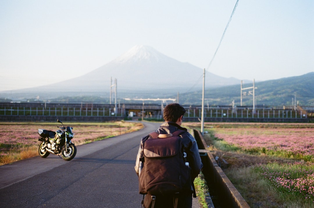 Un randonneur en couches chaudes vérifie son équipement avant l'ascension du mont Fuji, debout devant un refuge sur le sentier.
