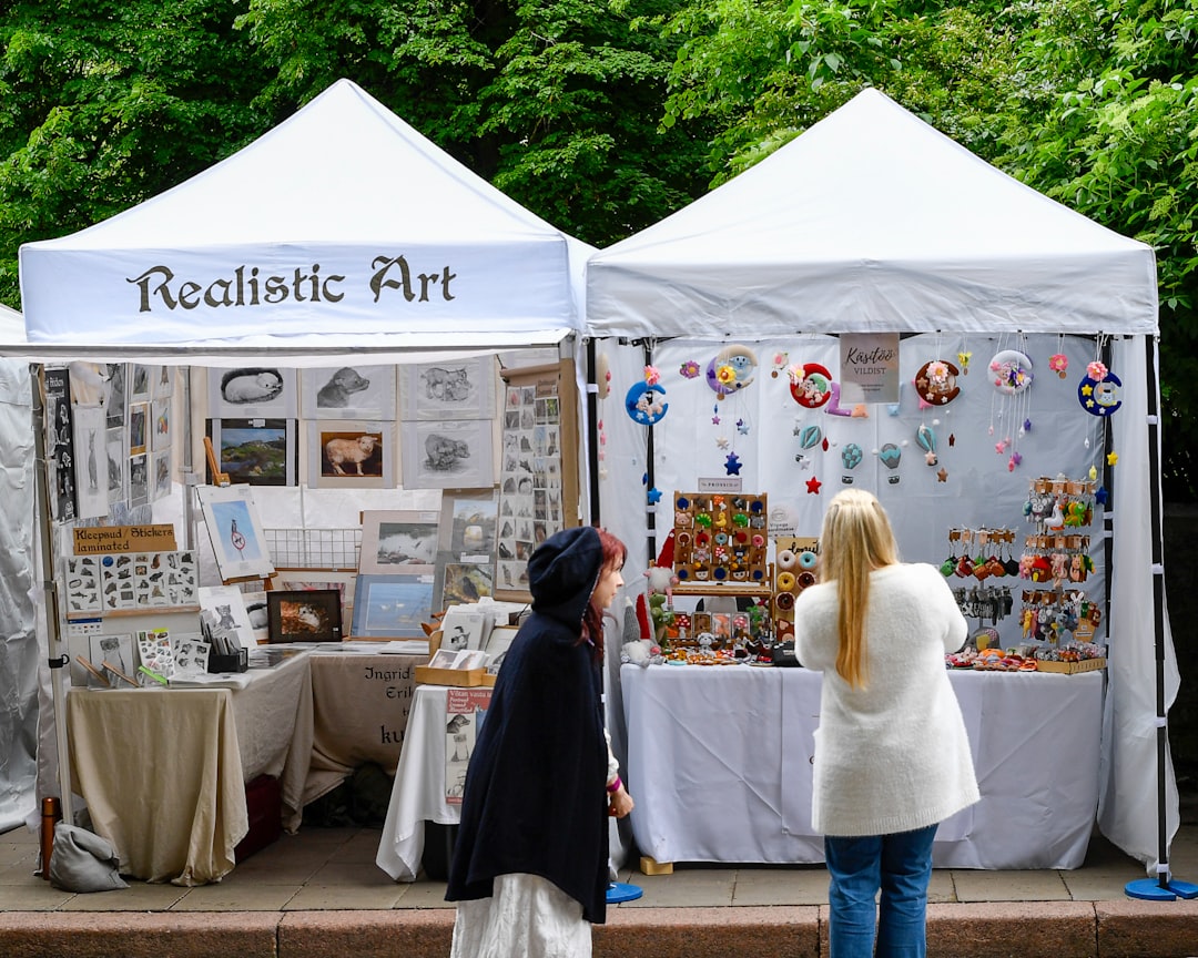 Due visitatori sfogliano prodotti fatti a mano e lavori di illustrazione in un mercato dell'arte all'aperto a Tokyo vicino a una sede sul lungomare.