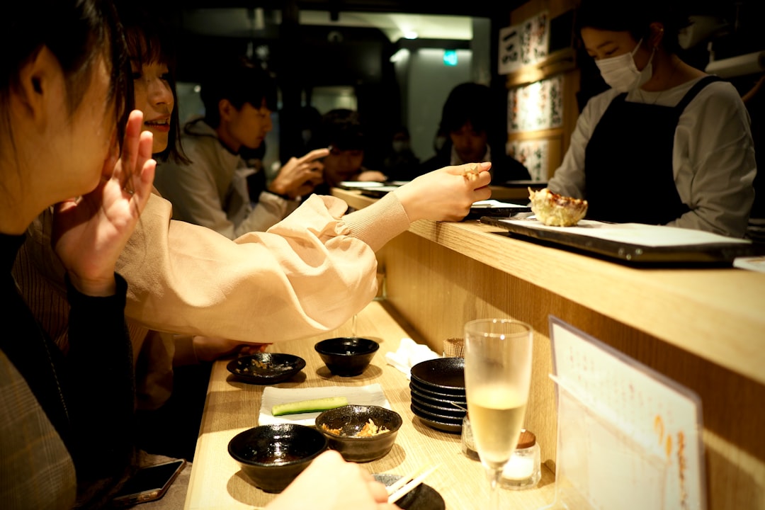 Um viajante usando um aplicativo de celular para encontrar um izakaya sem glúten em um bairro de Tóquio à noite