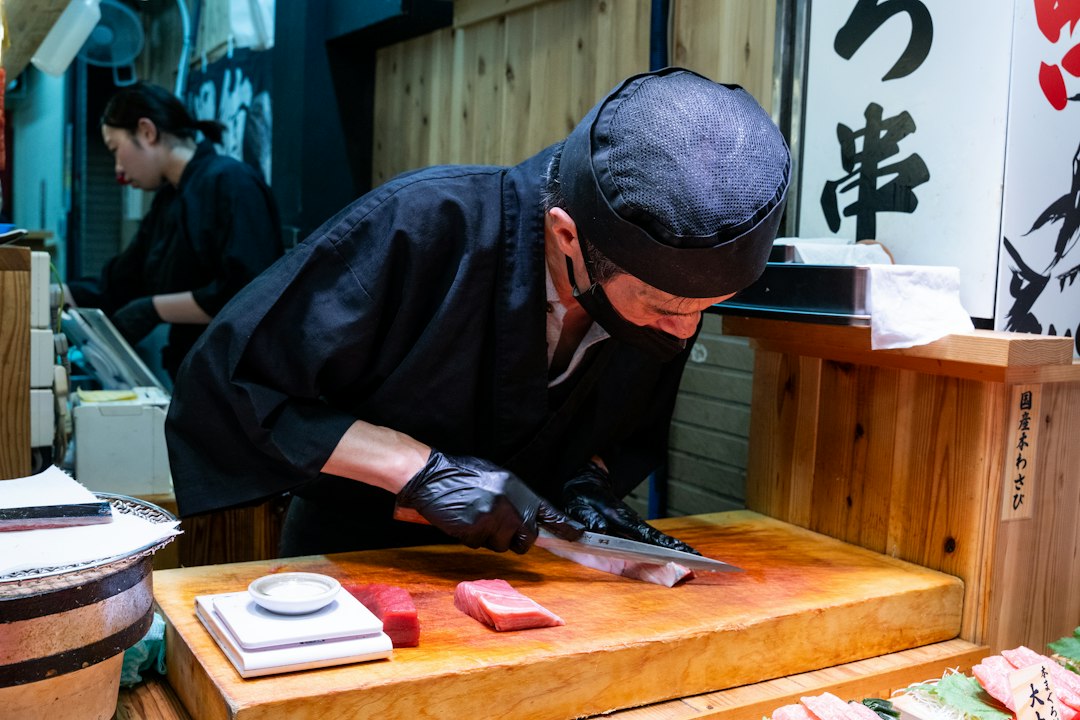 Chef sushi préparant des nigiri de balaou lors de la saison du sanma au marché de Toyosu