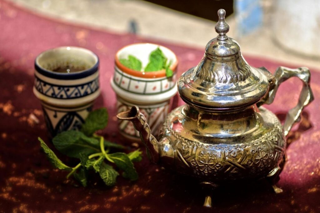 Traditional Moroccan gluten-free breakfast table with fresh mint tea, squeezed orange juice, and colorful salads, representing healthy naturally wheat-free morning meal honoring Moroccan culture