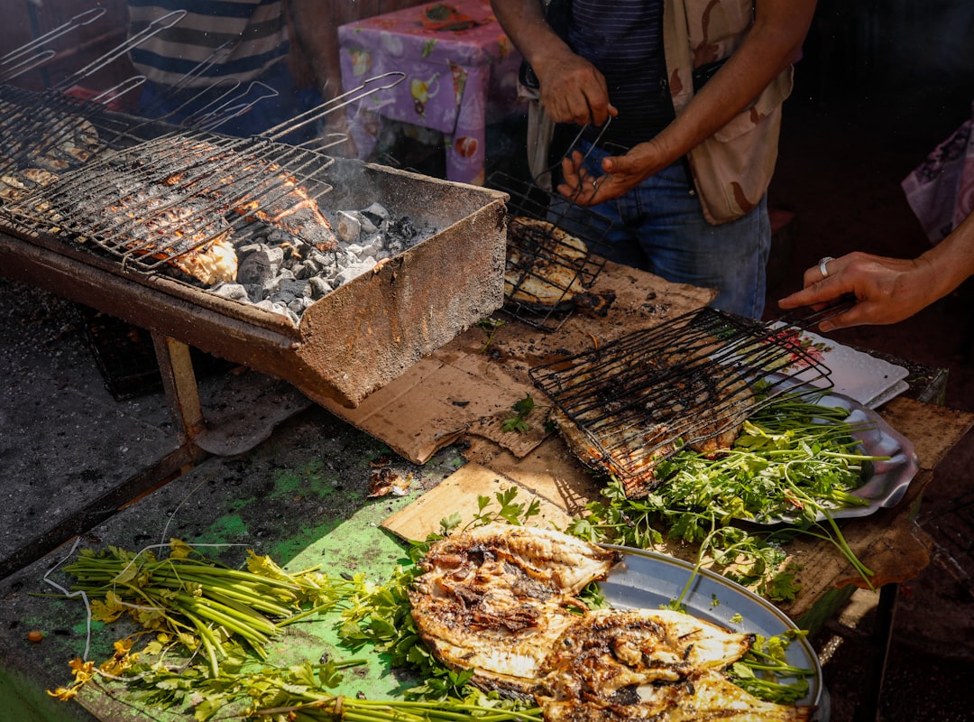 Un vendeur grillant de fraîches brochettes à un marché marocain, montrant la préparation à la chaleur qui rend la cuisine de rue plus sûre en été