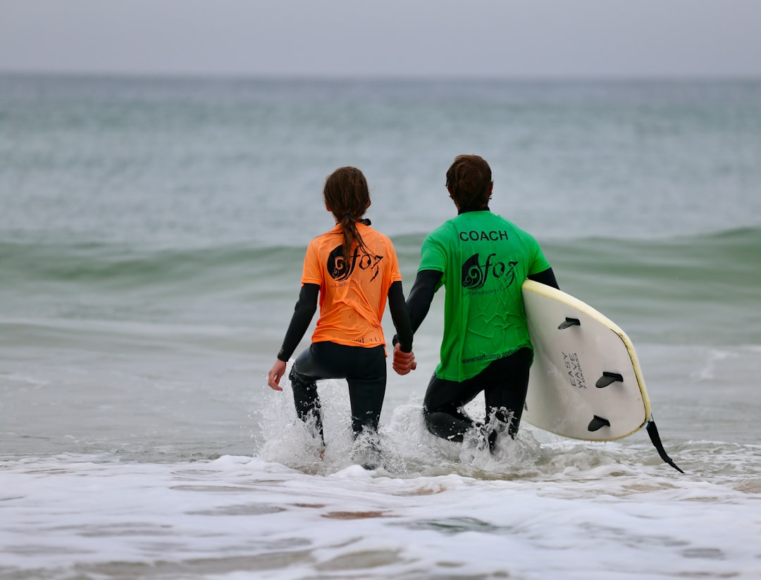 Un instructeur de surf guide un élève débutant dans une vague, une scène typique des camps de surf au Maroc en été