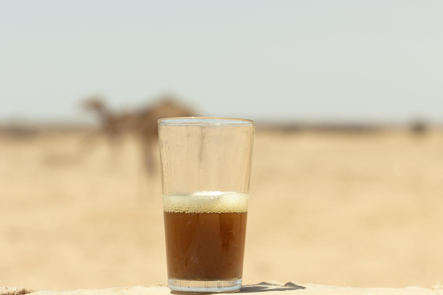 Um viajante segura um pequeno copo de chá de hortelã do Marrocos em um acampamento no deserto do Saara enquanto um guia berbere prepara a próxima rodada
