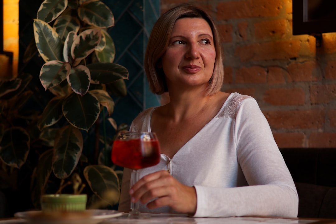 Uma mulher sorridente segurando um copo de vidro vermelho brilhante de suco de hibisco bissap, uma das bebidas marroquinas frias mais populares no verão