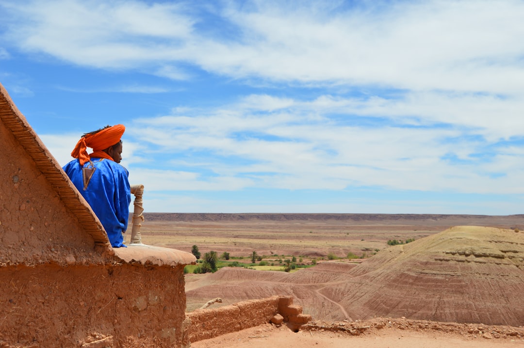 A woman rests on a guesthouse  in one of the most scenic Moroccan mountain villages, with green valleys visible.
