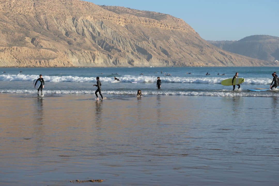 Uno studente in una scuola di surf in Marocco cavalca una dolce onda atlantica durante una sessione di coaching strutturata in estate