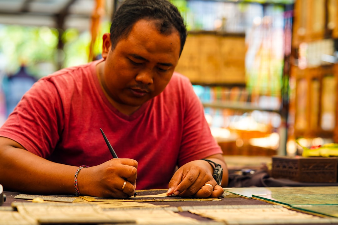 A craftsman carefully assembles a Moroccan mosaic geometric pattern face-down on the workshop floor