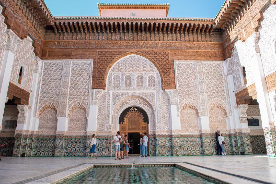 visitors stand inside a Moroccan riad courtyard surrounded by detailed Moroccan mosaic zellige tilework on the walls