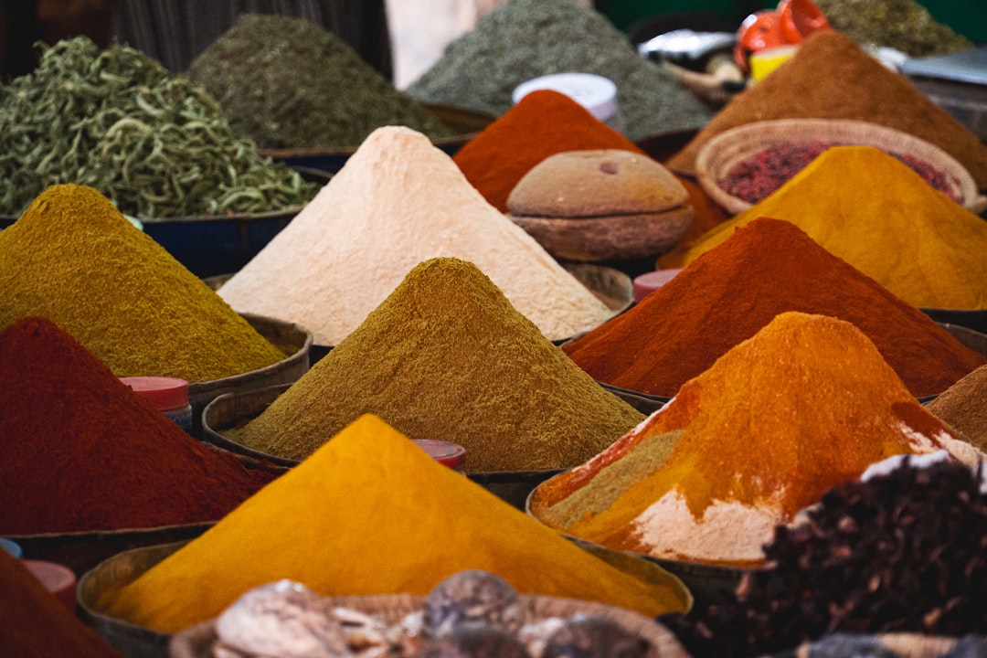 A woman selecting fresh souk ingredients including cinnamon and saffron at a Moroccan spice stall