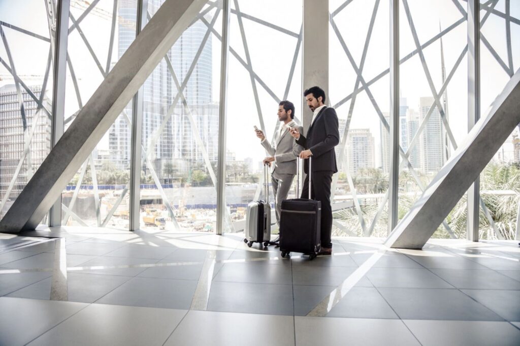 Two businessmen with luggage in Dubai business district startup ecosystem entrepreneurs funding innovation