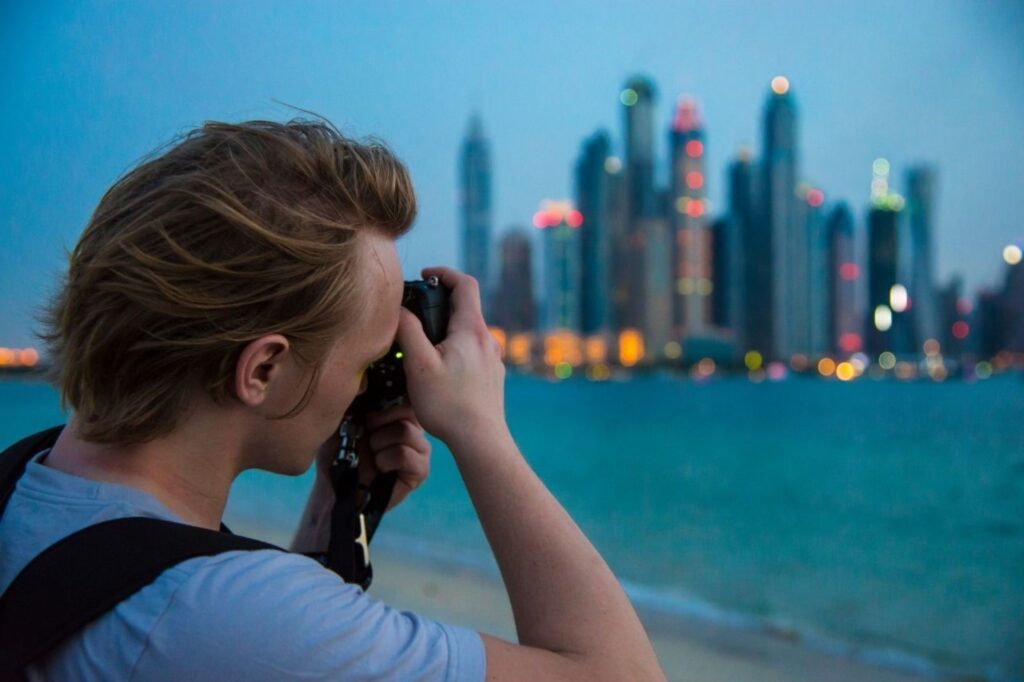 Professional photographer documenting luxury yacht photography at Dubai Marina waterfront with city skyline, representing top photography spots for travel content