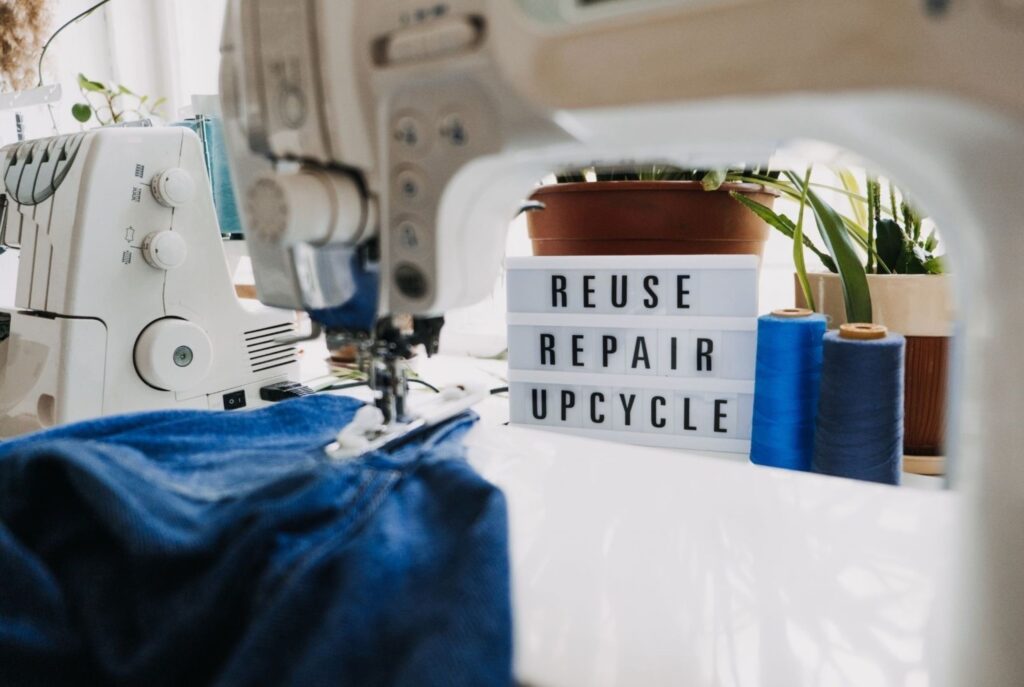 Sewing machine and upcycling materials in fashion design studio with reuse repair upcycle sign fashion designers upcycling sustainable circular creative