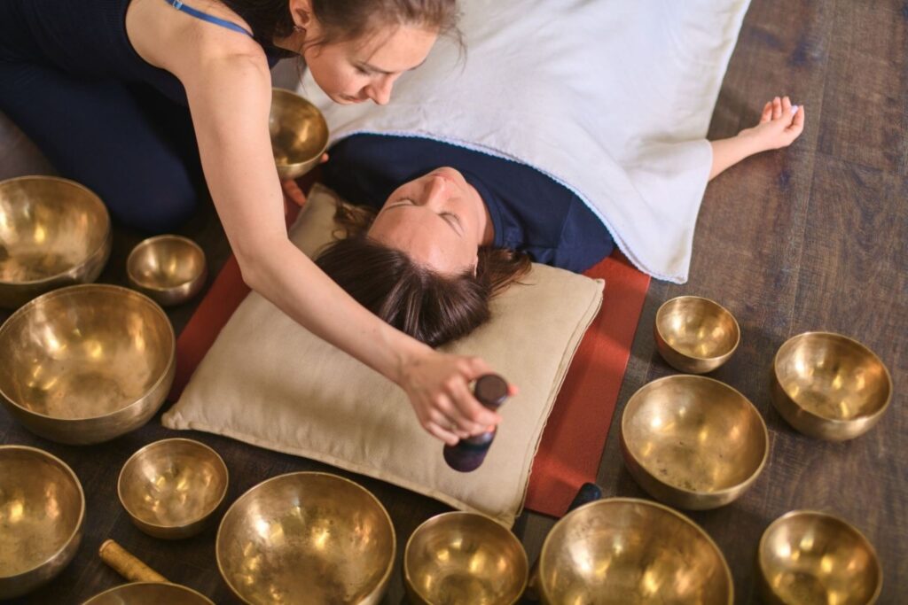 Woman experiencing sound bath with crystal bowls meditation sound healing wellness therapy vibrations balance