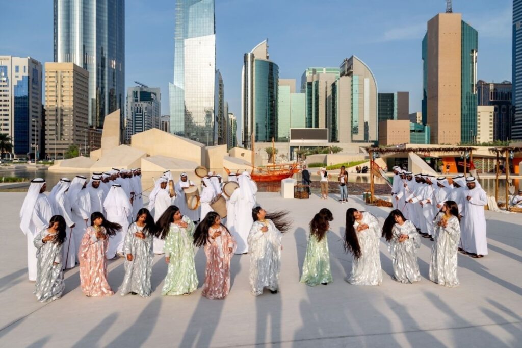 Emirati men and young girls performing traditional Al Ayala dance in colorful cultural attire during national day events, showcasing authentic UAE heritage celebrations in Dubai