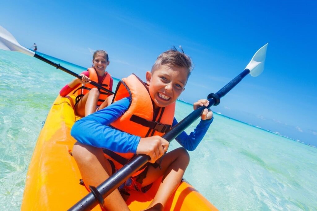 Family enjoying kayaking and paddleboarding beach sports at La Mer Dubai, representing accessible water activities suitable for all ages with calm conditions and professional instruction