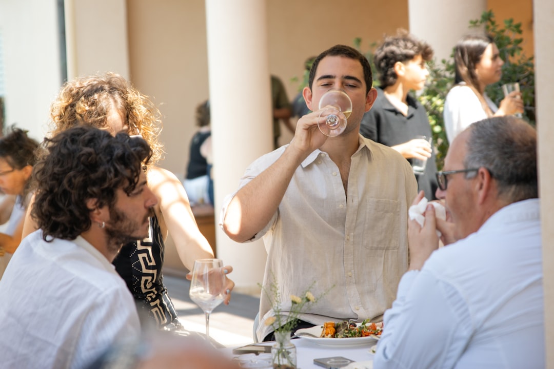 A group of friends enjoying a meal together at a members-only beach club in Dubai, with the sea visible in the background