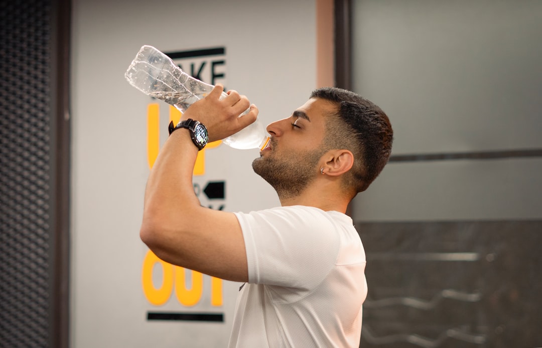 A male runner pausing his indoor training to hydrate, a critical part of preparing for a Dubai autumn race