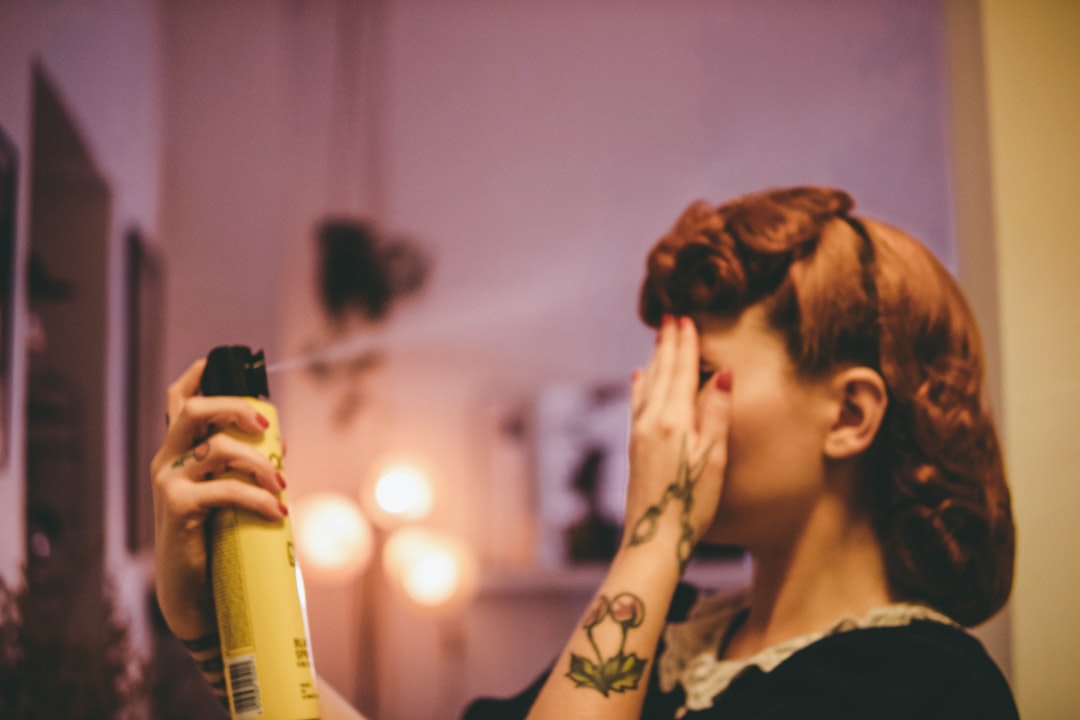 A woman using setting spray to seal her humidity makeup routine before stepping out in Dubai's August heat