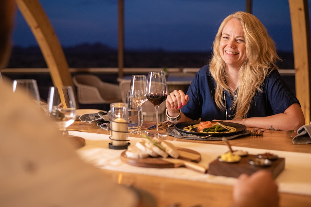 A woman seated at an outdoor table under a starlit desert sky, experiencing terrace dining in Dubai beyond the city